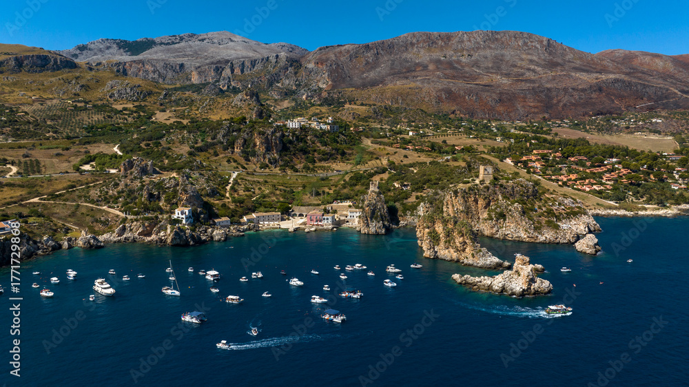 Obraz premium Aerial view of the Bay of Scopello, in the province of Trapani, Sicily, Italy. Boats are on vacation around the rocks in the Zingaro Nature Reserve. 