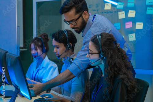 Customer support team in a modern call center receiving guidance from a supervisor. Diverse employees working with headsets and computers, representing teamwork, communication, and business 