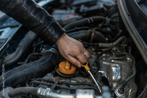 A close-up of a person's hand removing the oil dipstick from the engine. Routine maintenance, self-diagnosis, car care. The hand and the yellow dipstick are the main focus. Checking the oil level.