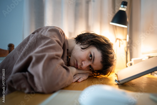 Exhausted burned out woman resting head on hands looking at camera. Tired female working late night desk with stress, mental exhaustion, overtime work stress, depressed female fatigue, overload