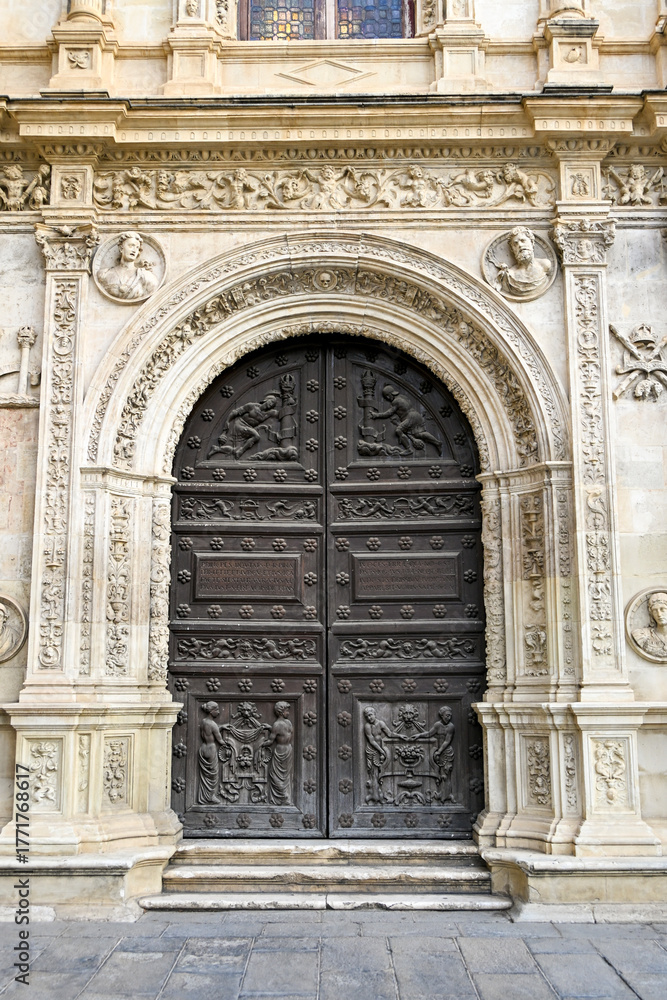 Fototapeta premium The renaissance wooden door with Latin inscriptions on the Plateresque facade of Seville Town Hall.