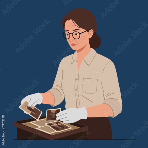 An older woman with glasses, gloved hands, examines old photos laid out in a tray. She wears a button-down shirt