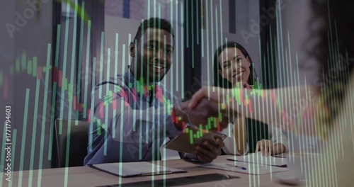 Shaking hand with entrant wearing business casual holding clipboard in boardroom with chart overlay