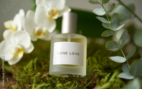 A frosted glass perfume bottle with the label lone love sits on moss