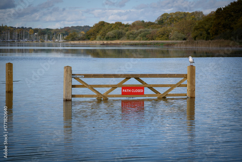 Flooded footpath blocked by a wooden gate and a red 'Path Closed' sign