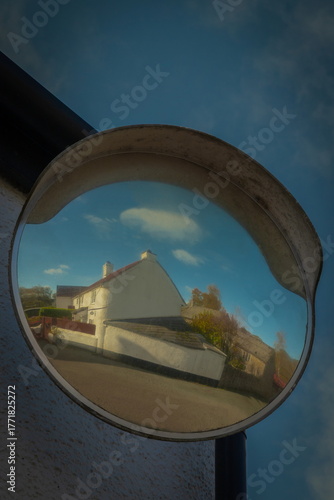 Building reflected in traffic mirror in village of Whitford, East Devon, UK