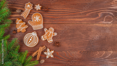 Fototapeta Naklejka Na Ścianę i Meble -  Christmas gingerbread cookies with icing, fir branches and cinnamon sticks on wooden table, festive holiday background with traditional handmade sweets and copy space for text