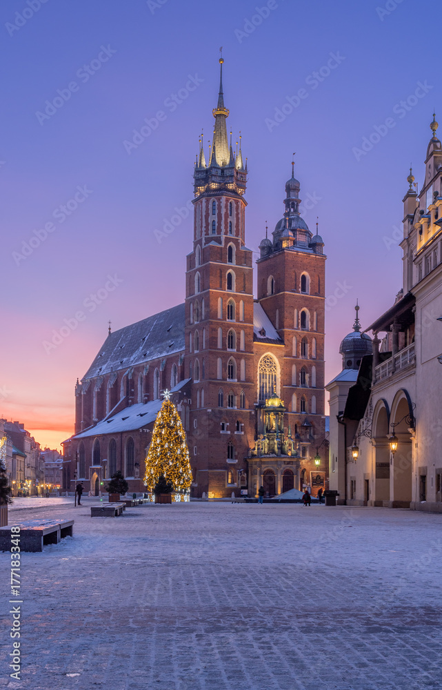 Obraz premium St Mary's church and Cloth Hall fragment on snow covered Main Square in winter Krakow, illuminated in the dawn
