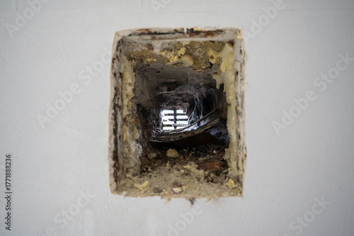 Closeup of neglected old ventilation hole in the wall of a house, covered with dust and cobwebs