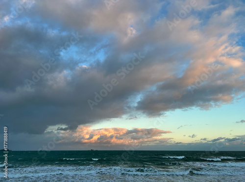 Sunset light over stormy Atlantic waves and wooden breakwaters, Brittany coast