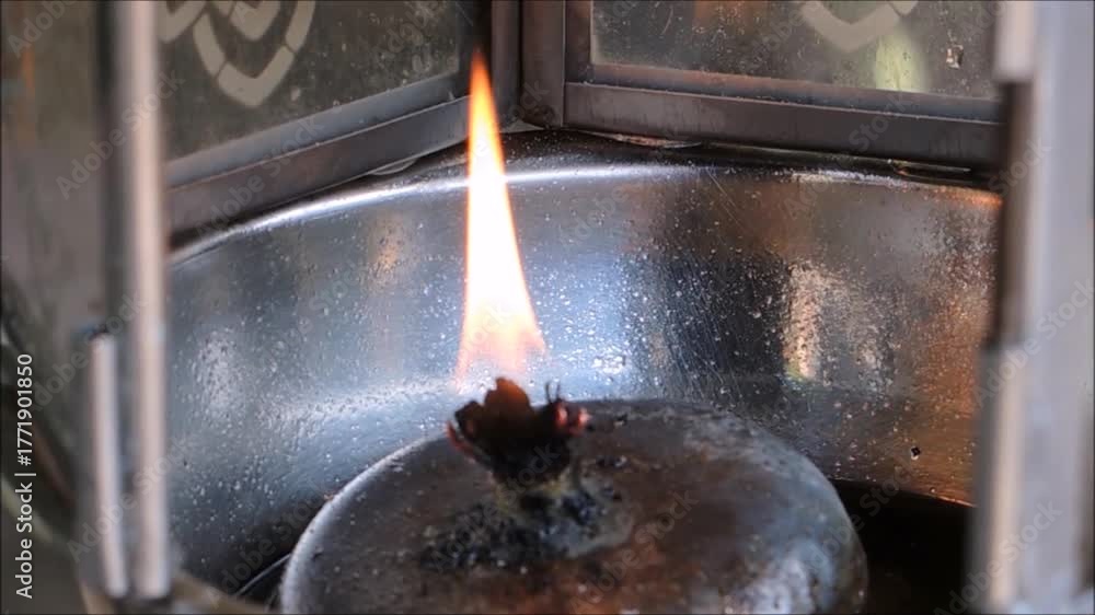 A fire burns in an oil lamp by the wick soaks up liquid oil through ...
