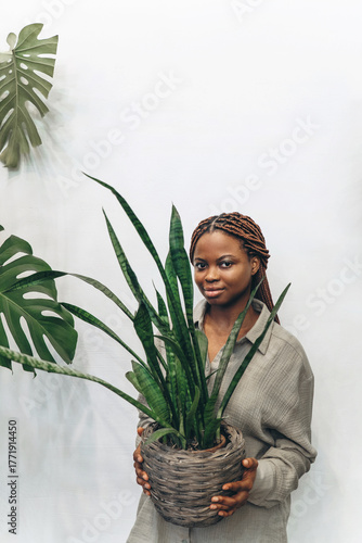 A woman holds a houseplant in a beautifully decorated modern setting