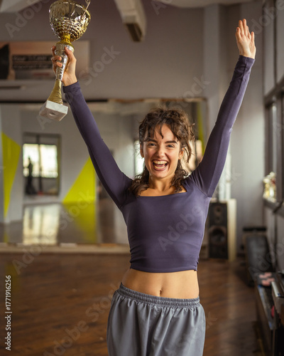 Canvas Print Young woman celebrating success holding gold trophy