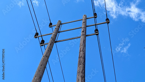 Wooden electricity telegraph poles carrying power lines against a clear blue summer sky