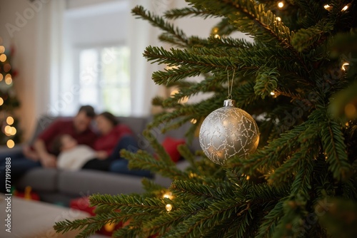 a family is sitting on the couch in front of a christmas tree