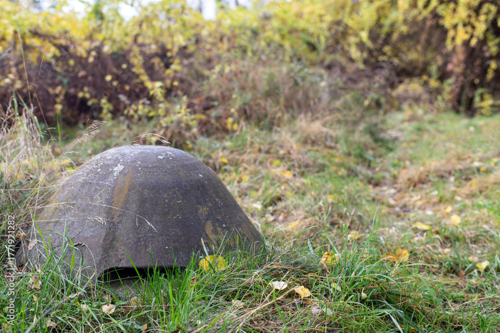 Naklejka premium Stalowa czapka schronu bunkra na tle pożółkłych jesiennych traw
