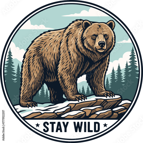 Grizzly bear standing on rocks in a snowy forest with the words stay wild