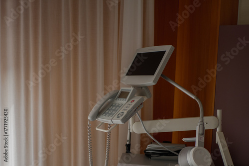 Modern hospital diagnostic monitor and communication device with medical cables and control panel in clinical room. High quality photo