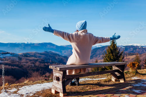 Canvastavla Back view of woman admiring landscape of winter Carpathian mountains sitting on bench