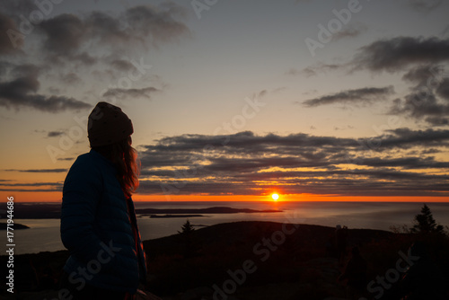 A person looks at the sunrise on Cadillac Mountain in Acadia National Park