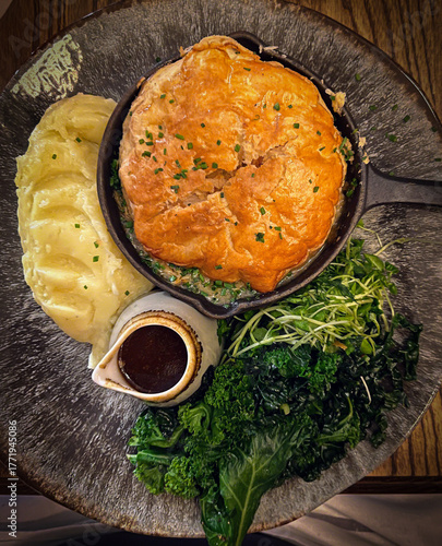 Chicken Pie and vegetables served on a plate with gravy in a jug