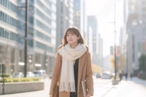 朝のオフィス街を歩くコートを着た女性