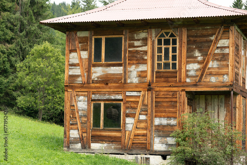 Rustic wooden house with weathered exterior and lush green surroundings in a peaceful rural setting