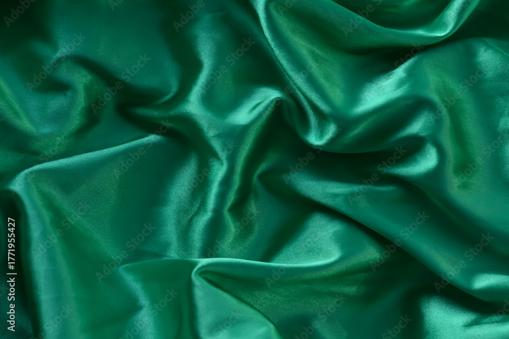 Fototapeta premium A closeup minimalist textured pattern. Green satin fabric texture luxurious shiny. Background with pattern soft waves blur beautiful.