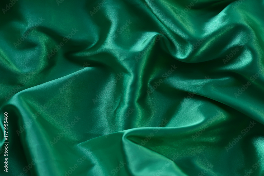 Fototapeta premium A closeup minimalist textured pattern. Green satin fabric texture luxurious shiny. Background with pattern soft waves blur beautiful.