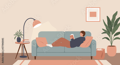 Young man reading a book while lounging on a sofa indoors  