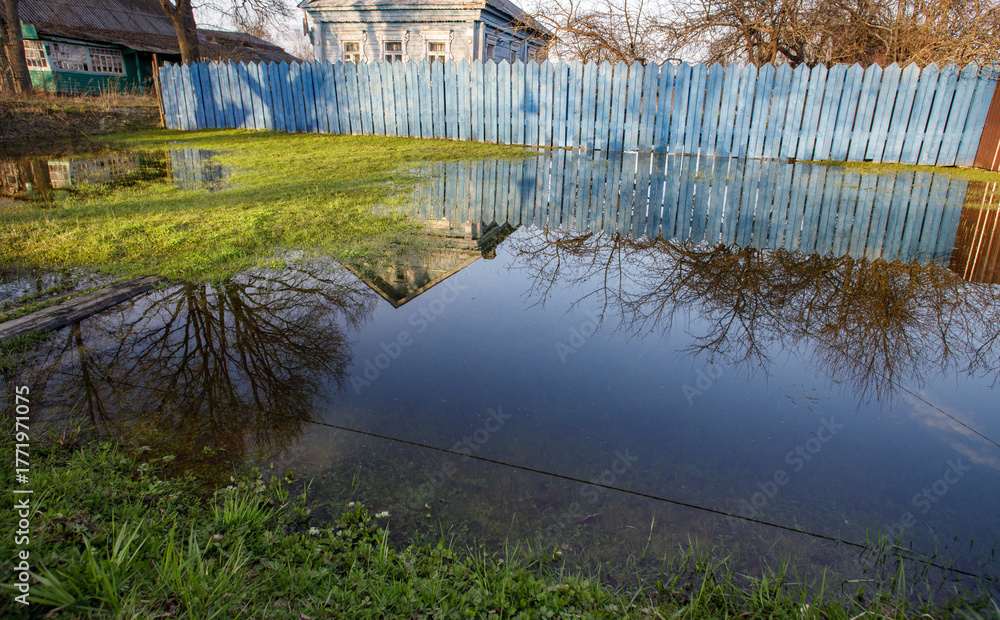 Fototapeta premium Blue fence surrounds a flooded yard