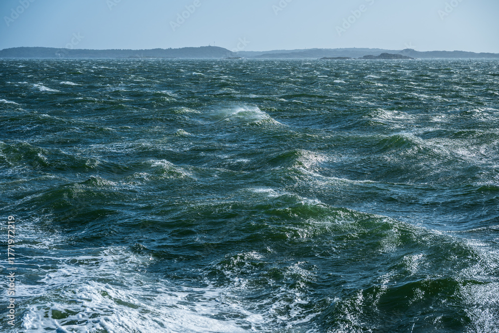 Fototapeta premium Choppy ocean waters under clear blue sky.