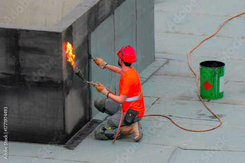 Un ouvrier du bâtiment utilisant un chalumeau pour sceller un mur avec un matériau d'étanchéité