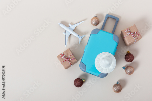 Fotografie Blue suitcase with white hat, airplane and holiday ornaments