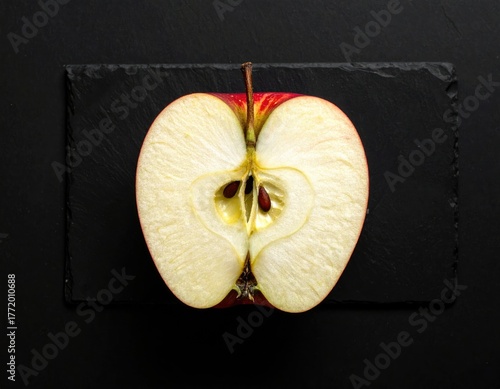 Close Up Shot Of A Halved Red Apple On A Black Rectangular Slate Against A Black Background