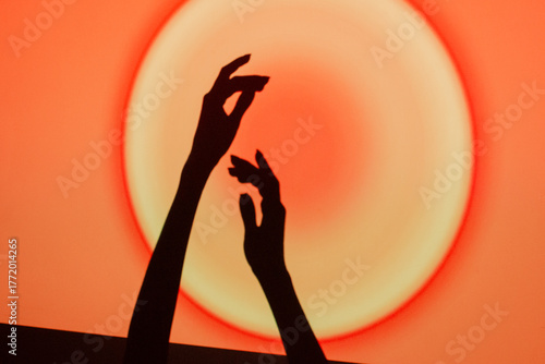 Hands reaching towards a glowing circle on a vibrant red and orange background during a creative event