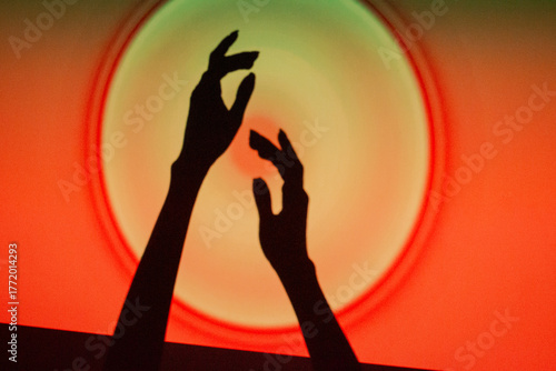 Hands reaching towards a glowing circle on a vibrant red and orange background during a creative event