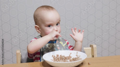 A truly delightful scene of a cheerful toddler who is happily eating from a bowl at a charming dining table