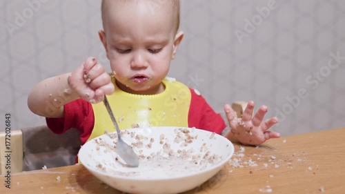 A cheerful toddler eagerly eats from a bowl, happily creating a delightful and colorful mess during mealtime