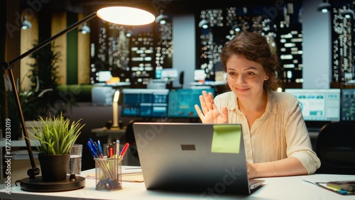 Businesswoman joins an online meeting at night in corporate office, maintaining eye contact with the camera. Manager focused on communication, participating in collaborative dialogue. Camera A.