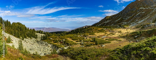 A panoramic view of the glacial basin surrounding the Small Jažinačko Lake (Liqeni i Vogël i Jazhincës) on the Šar Mountains, featuring alpine shrubs and rocky terrain