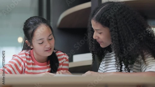 Two teenage girls reading a book together	
