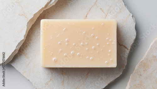 Organic bar soap with delicate bubbles on a natural stone surface, highlighting skincare, purity, hygiene, and beauty in a minimalist flat lay composition
