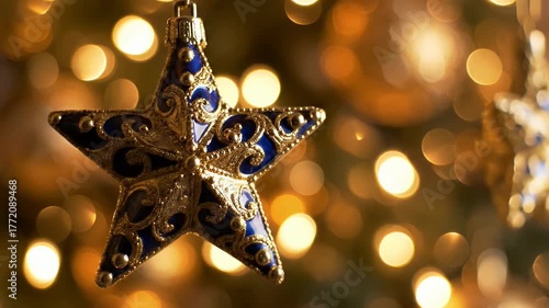 Close Up Shot of Ornate Blue and Gold Star Ornament Hanging with Defocused Christmas Lights in Background