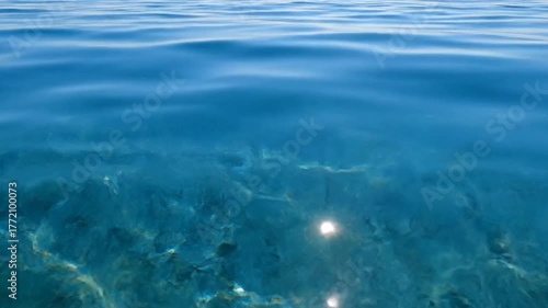 Sunlight Reflecting on Rippling Clear Turquoise Water Surface with Visible Seabed Texture in Underwater Scene Perfect for Background and Wallpaper