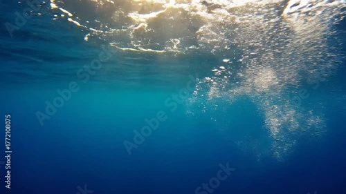 Sunlight Streams Through Surface Of Blue Ocean Water With Sparkling Bubbles Creating A Tranquil Underwater Scene Ideal For Stock Photography