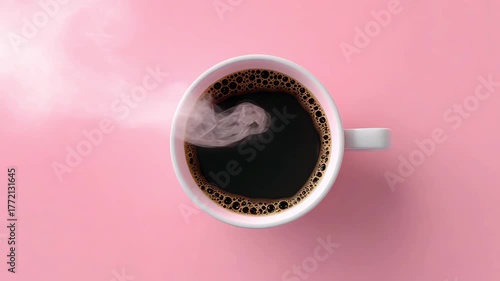 Top view of a steaming coffee cup filled with dark coffee on a pastel pink surface, 4k video