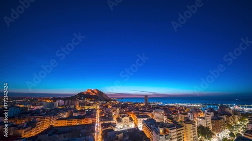 Night Timelapse of Cityscape at dusk with illuminated castle on hill.