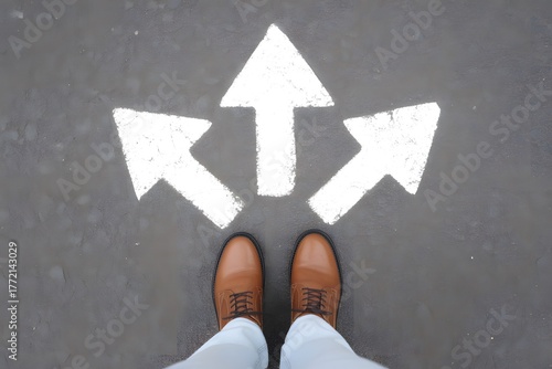 Person s feet standing at three way arrow intersection on road