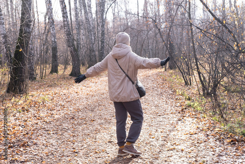 Happy, smiling 40-year-old woman enjoys the warm, sunny weather in an autumn park. Hello, autumn!